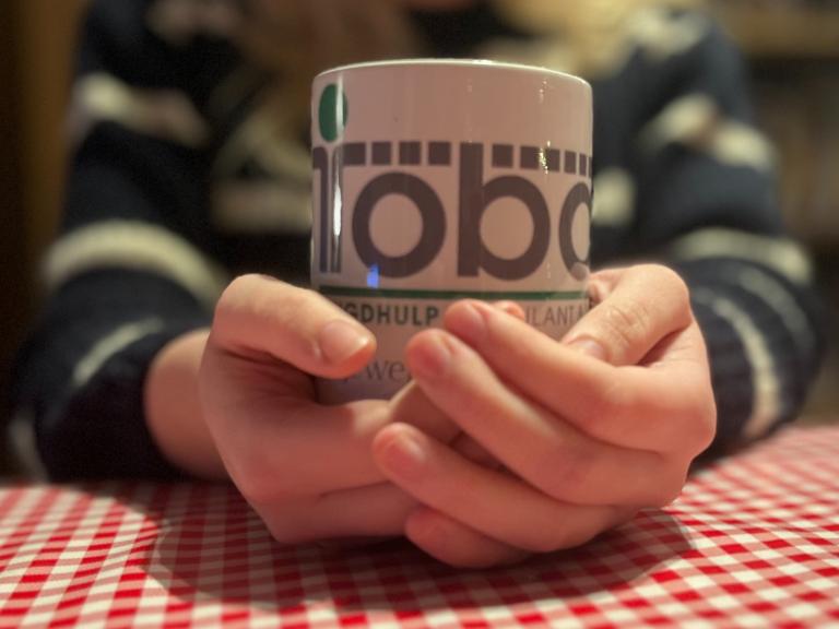 Koffiemok Tobas met twee handen vastgehouden